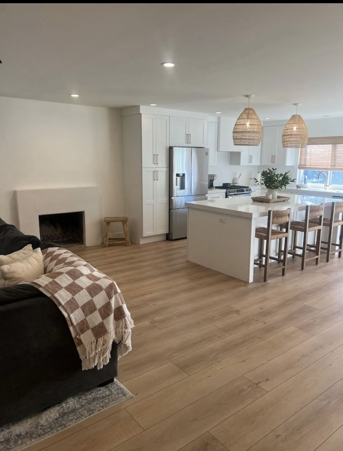 A finished open-plan kitchen and living room with wood flooring and an island with seating.