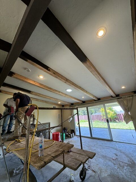 Exposed wood ceiling beams and recessed lighting during an interior remodel.