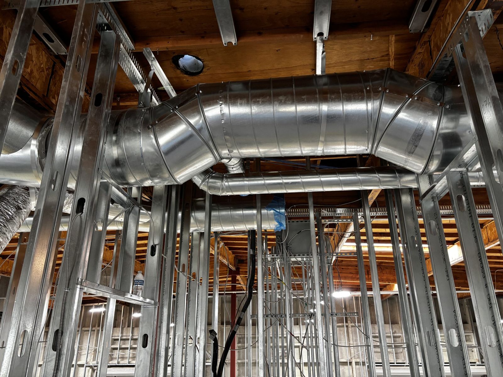 A round spiral duct running through open ceiling framing on a commercial job.