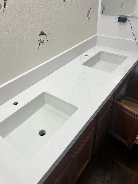 Two undermount sinks set into a white quartz vanity top.